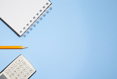 Notepad, calculator and pencil on blue backgroundの写真素材