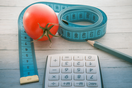 Measuring tape and calculator with juicy tomato, concept of healthy eating and slimming, close-upの写真素材