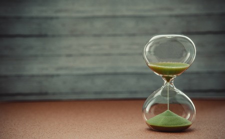 Sand running through the bulbs of an hourglass measuring the passing time in a countdown to a deadline, on a blur background with copy spaceの写真素材