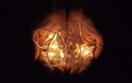 Lights in the palms. Women's hands holding a garland, warm Christmas mood, soft focus