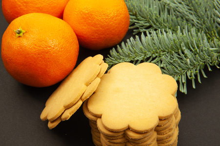 Ginger cookies, fir branches and tangerines, on a dark background, close-upの写真素材