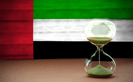 Hourglass on the background of the UAE flag, the concept of time and countries, space for textの写真素材
