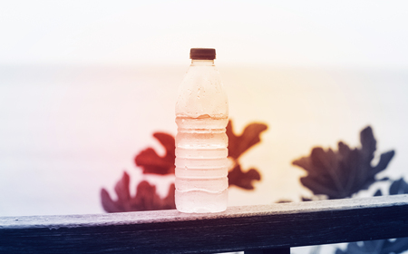 A bottle of clean drinking water on a natural background with a red light, the concept of purity and healthの写真素材