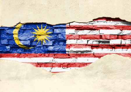 National flag of Malaysia on a brick background. Brick wall with partially destroyed plaster, background or texture.の写真素材