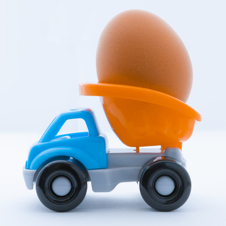 Colorful toy truck with a chicken egg in the back on a white backgroundの写真素材