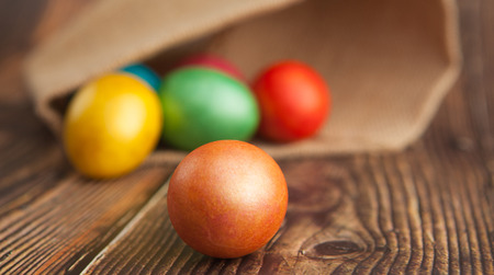 Colored Easter eggs on a wooden background in burlap with blurred background, close-upの写真素材