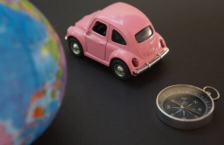 Car and globe with compass on black background, travel symbol around the world