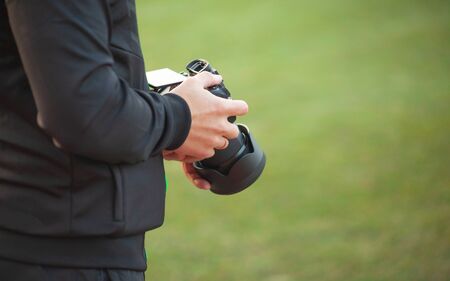 A man holds a camera in his hands on a blurry green background, a professional photographer makes...