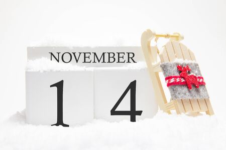 Autumn calendar made of wooden cubes with the date of November 14, the concept of the first snow and future holidays. Close-up.の写真素材