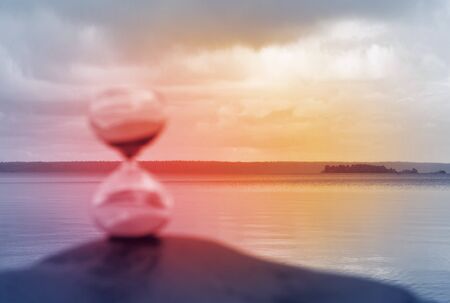 Blurred hourglass on a rock, illuminated in red as a concept of lost time.の写真素材