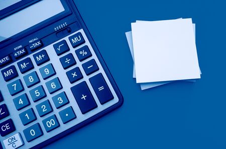 Modern calculator with stickers for notes on a yellow background, toned trendy classic blue color of year 2020の写真素材