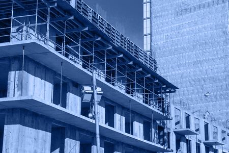 The process of construction of multistory monolithic building. Concrete and metal frame of floor slabs and columns. Toned trendy classic blue color of year 2020の写真素材