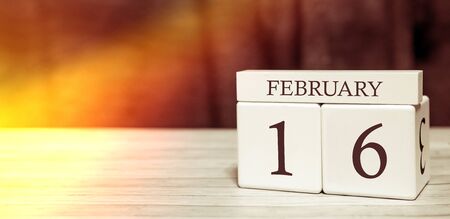 Calendar reminder event concept. Wooden cubes with numbers and month on February 16 with sunlight.の写真素材