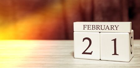 Calendar reminder event concept. Wooden cubes with numbers and month on February 21 with sunlight.の写真素材