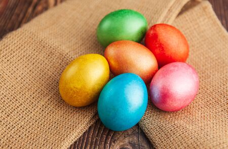 Colored easter eggs on a wooden background on burlap, top viewの写真素材
