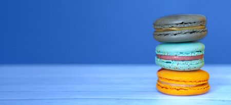 Colored macaroons on blue classic background, french cookies as a treat for the holiday, space for textの写真素材