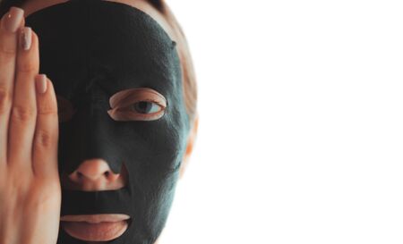 Close-up young woman with a purifying black mask on her face, Isolated on white background