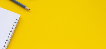 Notebook, pencil on a yellow background. Top view space for copy or text.