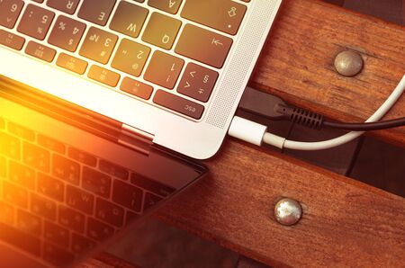 Notebook keyboard and two wires with sunshine close-up on a benchの写真素材