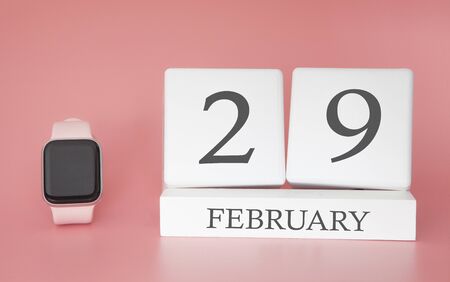 Modern Watch with cube calendar and date 29 february on pink background. Concept winter time vacation.の写真素材