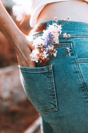 The girl stands with her back in blue jeans, flowers in her back pocket.の写真素材