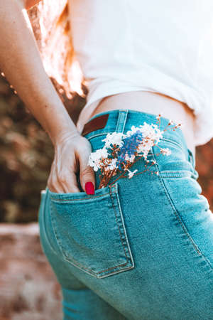 Flowers in the back pocket of blue jeans, a beautiful girl in jeansの写真素材