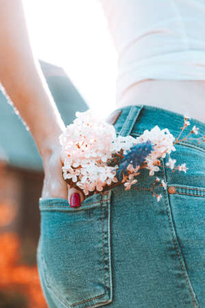 Flowers in the back pocket of blue jeans, a girl with red manicureの写真素材