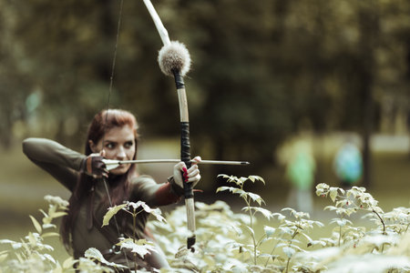Archer woman shooting the bow and arrow in the swamp.