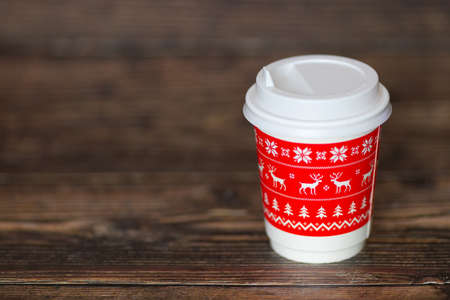 Coffee to go is on the wooden table. Christmas mood is a warm beverage. Mulled wine tea winter take away drink. Reusable zero waste mug. Blurred background.の写真素材