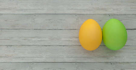Colored Easter eggs yellow and green on a light wooden backgroundの写真素材