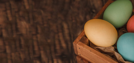 Easter holiday. Wooden box with colored Easter eggs on a wooden background.の写真素材