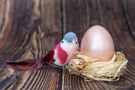 Easter egg in the nest and pink bird. Dark wooden backgroundの写真素材