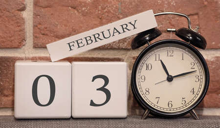 Important date, February 3, winter season. Calendar made of wood on a background of a brick wall. Retro alarm clock as a time management concept.の写真素材