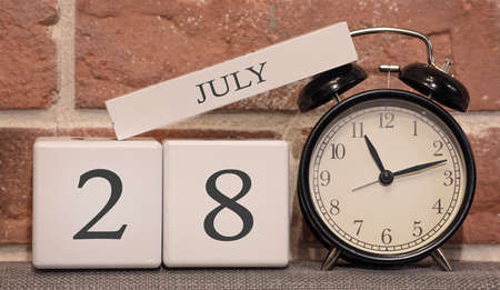 Important date, July 28, summer season. Calendar made of wood on a background of a brick wall. Retro alarm clock as a time management concept.の写真素材