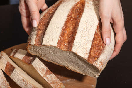 Female hands hold freshly baked bread. Homemade baking.