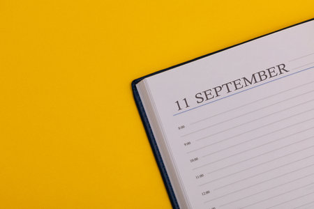 Notepad or diary with the exact date on a yellow background. Calendar for September 27 - fall time. Space for text.の写真素材
