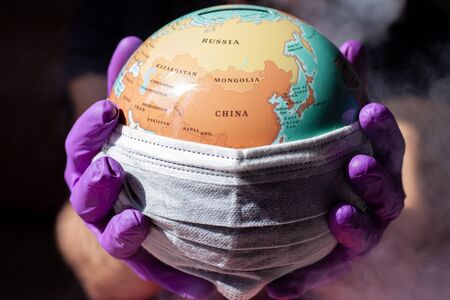 World Epidemic Danger. World need protect the earth globe with a face mask and hands, isolated on a...