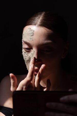 Organic cosmetic mask (scrub) with natural extracts in woman face. Black backgroundの写真素材