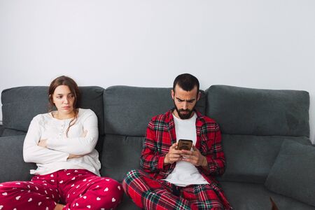 Young couple sitting on a white sofa separately after an argument