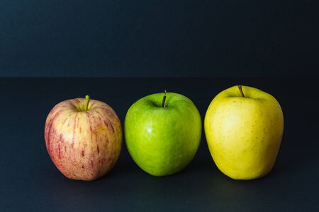 3 different colors of fresh apples on black backgroundの写真素材