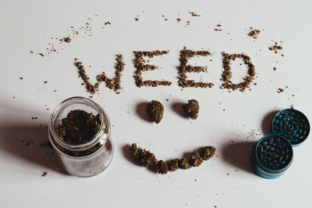 The word WEED and smile face spelled out with marijuana, buds and scatter leaves, on white.の写真素材