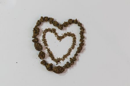 Two signs hearts spelled out with marijuana and buds on white background