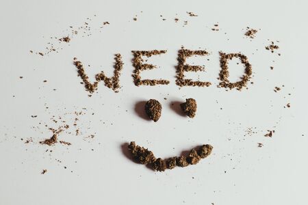 The word WEED and smile face spelled out with marijuana, buds and scatter leaves, on white.の写真素材