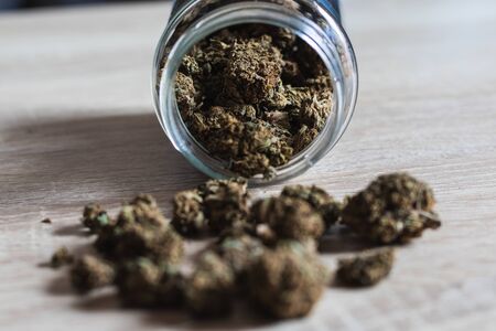 Jar with buds of weed on wooden background