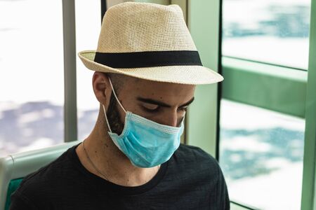 Stock photo of man using mobile phone in the public bus. He is wearing a protective mask for the prevention of a virus. Coronavirus conceptの写真素材