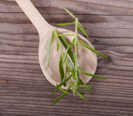 Rosemary on spoon over wooden tableの写真素材