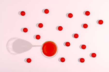 Flat lay concept. Light pink background. Red glittery Christmas balls like cherry candies. An...
