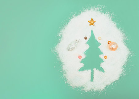 Pastel mint concept. Christmas tree silhouette. with copy space. New Year's decorations in caramel and pastel color. Pearl white silver cone. Small balls and a copper Christmas star. Blown snow.の写真素材