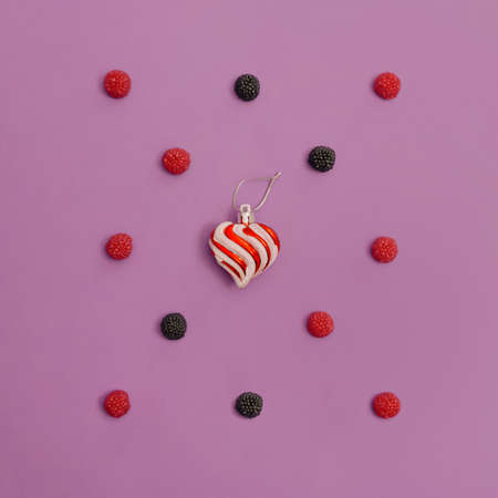 Heart and fruit creative concept. Pink and purple raspberries and blackberries. Sweet fruits on a...