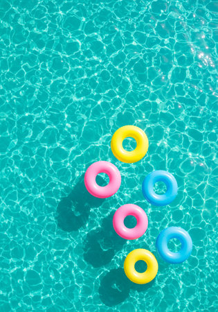 Colorful inflatable rings floating in a swimming pool on a sunny dayの素材